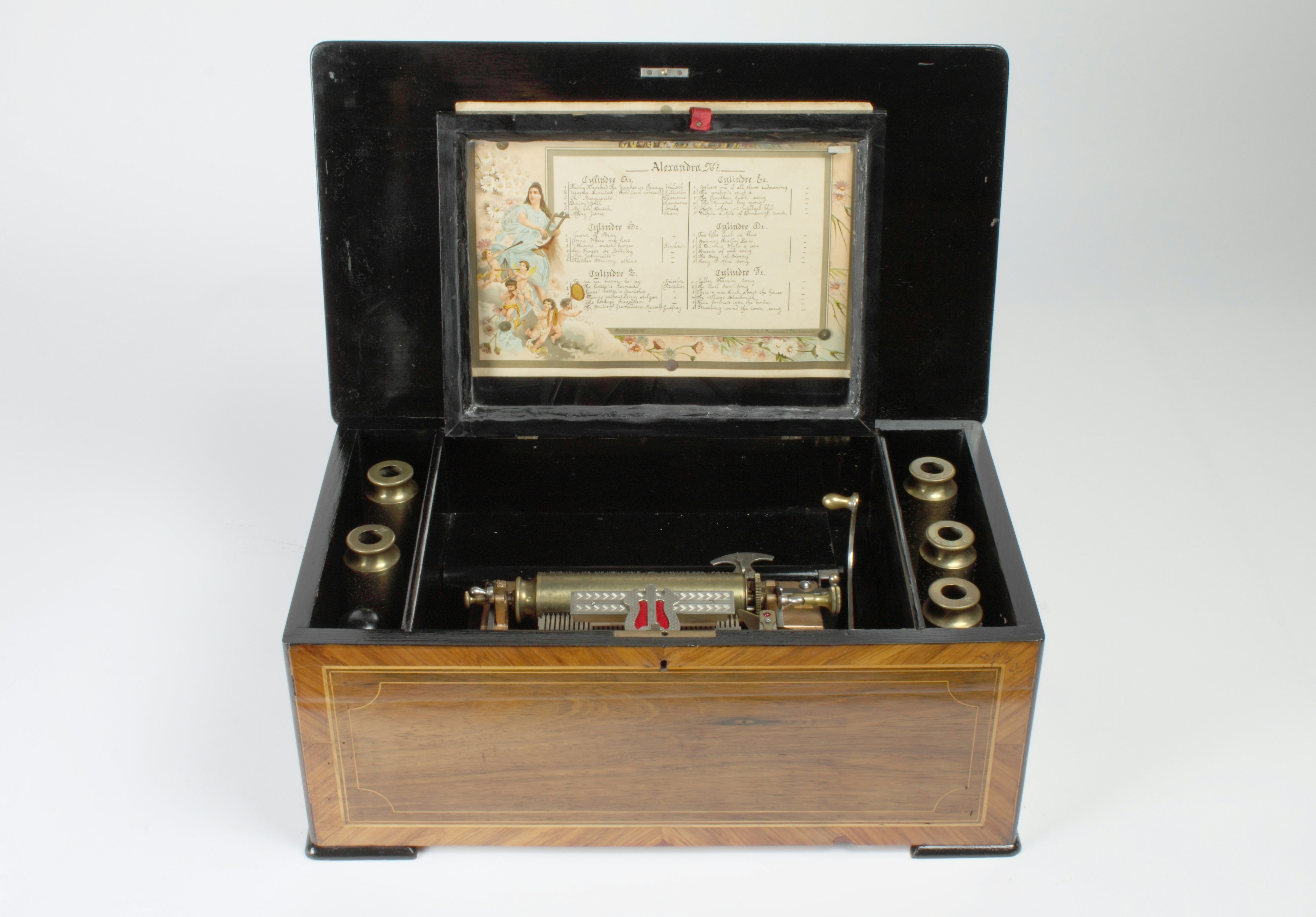 Auswechselbare Zylinderhülsen mit je 6 Musikstücken; Stimmkamm mit 41 Tönen. 52 x 31 x 22 (48,5) cm (L. x T. x H., ( ) H. mit geöffnetem Deckel).