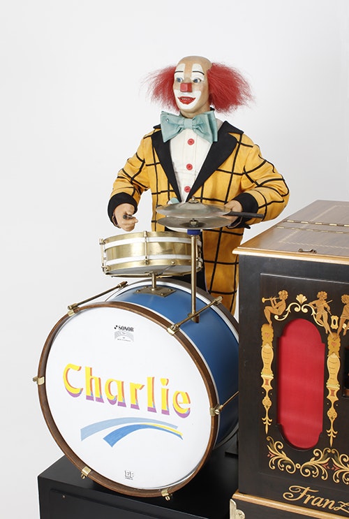Charlie mit seiner Schlagzeugbatterie wird von einer Drehorgel begleitet.